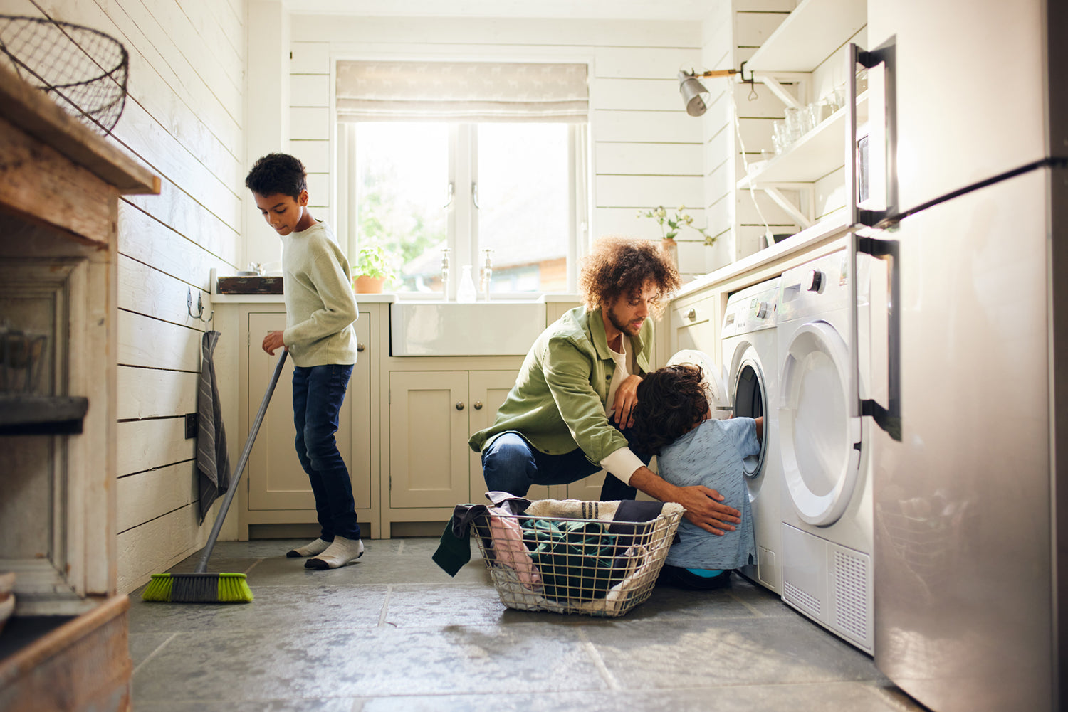 Dad and two sons cleaning laundry room.